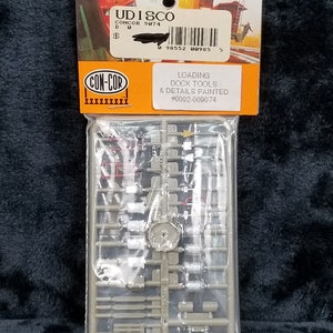 May include: A plastic bag containing a model kit for a loading dock with tools and details painted. The kit is labeled "CON-COR" and "#0002-009074".