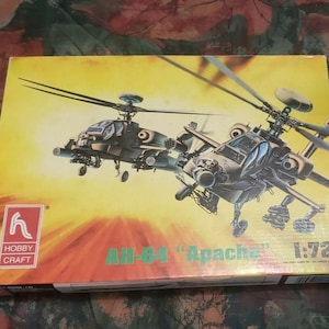 May include: A yellow box with a picture of two military helicopters, an AH-64 Apache, on the front. The box is labeled "Hobby Craft" and "AH-64 "Apache" 1:72".