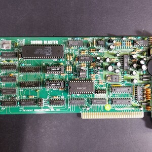Könnte beinhalten: Eine grüne Sound Blaster Soundkarte mit mehreren Chips und Steckverbindern. Die Karte trägt den Text "SOUND BLASTER" und "COPYRIGHT CREATIVELINK 1990".