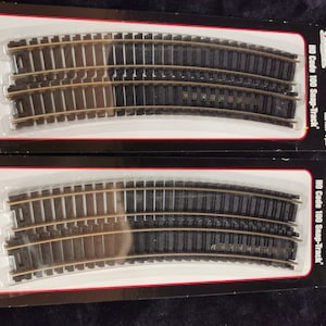 May include: Two packs of Atlas HO Code 100 Snap-Track model railway track. Each pack contains a 22-inch radius section of track.