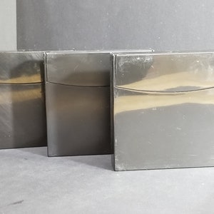 Peut inclure: Trois contenants de rangement rectangulaires noirs avec un bord supérieur légèrement incurvé.