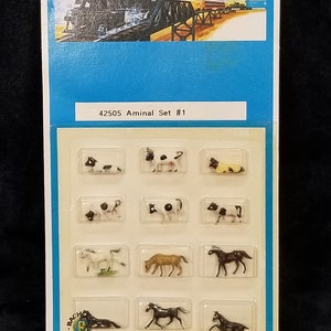 May include: A plastic blister pack containing a set of 12 miniature farm animals. The animals are painted in realistic colours and include cows, horses, and pigs. The package is labelled "42505 Aminal Set #1" and "IMPORTED PARTS MADE IN CHINA/PRINTED IN HONG KONG".