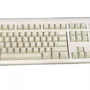 Könnte beinhalten: Eine weiße Computer-Tastatur mit Standardlayout, einschließlich Funktionstasten, Zifferntasten und Pfeiltasten. Die Tastatur hat eine beige Farbe und eine leicht strukturierte Oberfläche.