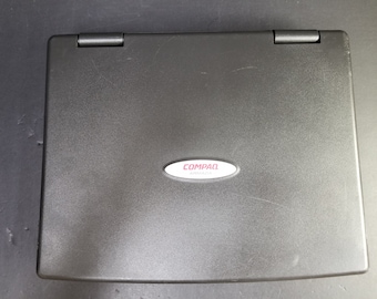 Puede incluir: Un ordenador portátil Compaq Armada negro con un logotipo plateado.