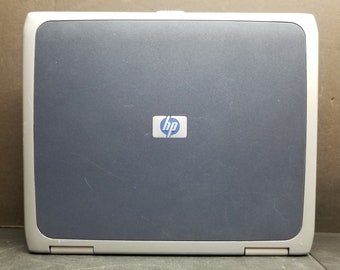 Puede incluir: Un ordenador portátil HP plateado y azul con un logotipo HP plateado en la tapa.