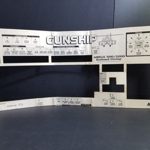 Könnte beinhalten: Ein schwarz-weißes Tastatur-Overlay für den Amiga 500/2000 Computer. Das Overlay ist für das Spiel Gunship konzipiert und zeigt eine Hubschraubergrafik sowie verschiedene Kontrollbeschriftungen.