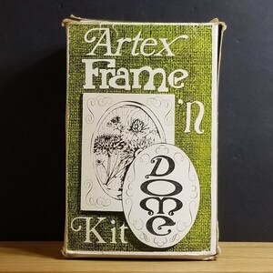 May include: A green box with the text "Artex Frame-in Kit" and a black and white illustration of a flower. The box is for a craft project.