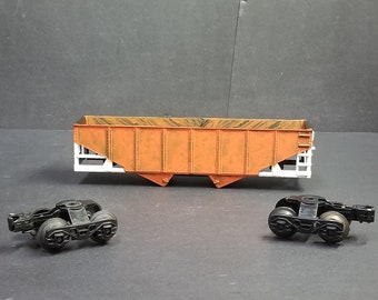 May include: A model train car with a brown and white body and black wheels. The car is a hopper car, which is used to transport loose materials like grain or coal.