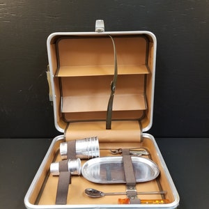 Puede incluir: Un juego de bar de viaje vintage de aluminio plateado con interior de cuero marrón. El juego incluye una bandeja, cuatro tazas, un abridor de botellas, una coctelera, una cuchara y un agitador.