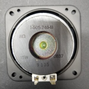 Pu&ograve; includere: Primo piano di un driver per altoparlanti con il numero di modello 1-505-748-11, 8 ohm, 15W e 9 035 stampato sul davanti. Il driver per altoparlanti &egrave; montato in una cornice di plastica nera.