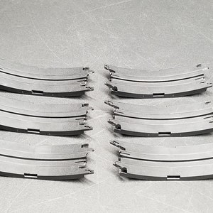 May include: Six black plastic curved track pieces for a toy race car set.