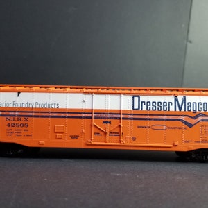 Może przedstawiać: Pomarańczowy i biały model wagonu kolejowego z nadrukiem "Superior Foundry Products" i "Dresser Magcobar Division of Industries Inc." na boku. Wagon ma numer "N.L.R.X. 42568" nadrukowany na boku.