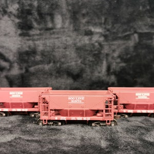 May include: Three red model train cars with the words "Soo Line Railroad" printed on the side. The middle car has the number "51570" printed on it.