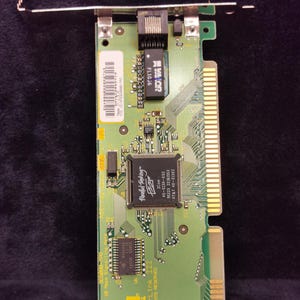 May include: A green circuit board with a network card, a chip labeled "3Com EtherLink II", and the text "Parallel Tasking" on the chip. The board has a RJ-45 connector and a 3Com logo.