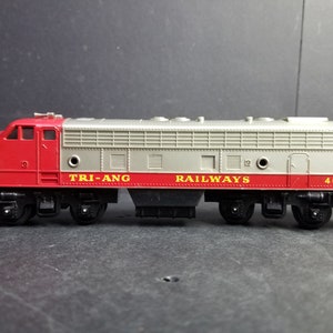 May include: A red and silver toy train engine with the words "TRI-ANG RAILWAYS" and the number "4008" printed on the side.