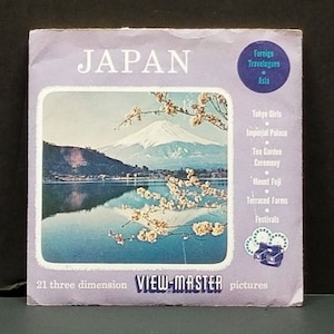 May include: A purple and white View-Master reel box with a picture of Mount Fuji and cherry blossoms. The text on the box reads "JAPAN" and "21 three dimension VIEW-MASTER pictures".