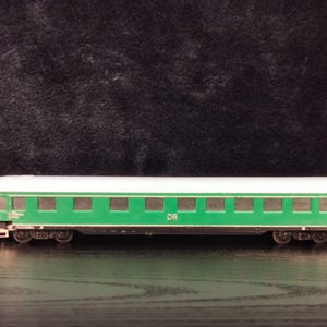 Può includere: Un vagone di treno modello verde e bianco con le lettere "DR" stampate sul lato.