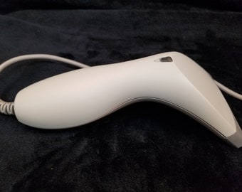 May include: A white handheld barcode scanner with a black cord. The scanner has a curved design and a small window on the top.