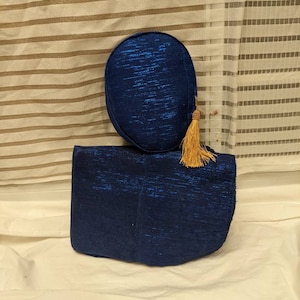 May include: A blue fabric pouch with a matching blue fabric hat with a gold tassel.