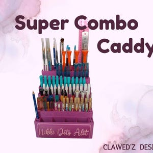May include: A purple Super Combo Caddy filled with various art tools, including paintbrushes, pens, and other supplies. The caddy has multiple compartments and a ruler. The text "Nikki Dots Alot" is visible on the front.
