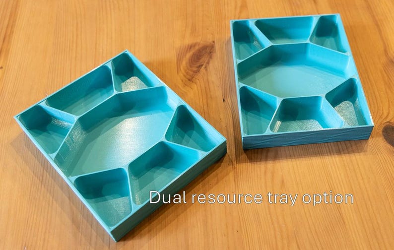 May include: Two rectangular turquoise plastic trays, each featuring a central hexagonal compartment surrounded by six smaller, irregularly shaped sections. The text "Dual resource tray option" is printed in white at the bottom center.
