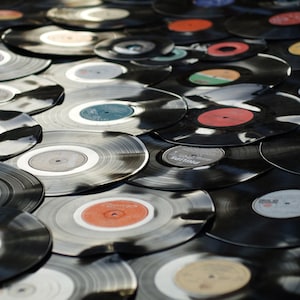 May include: A collection of vintage vinyl records in various colors, stacked and overlapping. The records are black with colorful labels.