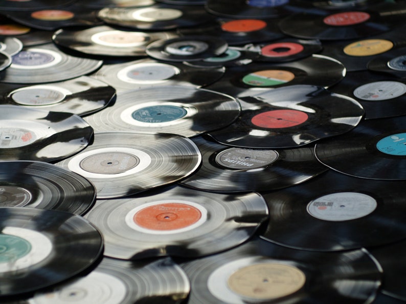 May include: A collection of vintage vinyl records in various colors, stacked and overlapping. The records are black with colorful labels.