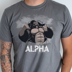 May include: A gray t-shirt with a graphic of a gorilla breaking through a wall with the word "ALPHA" printed below.