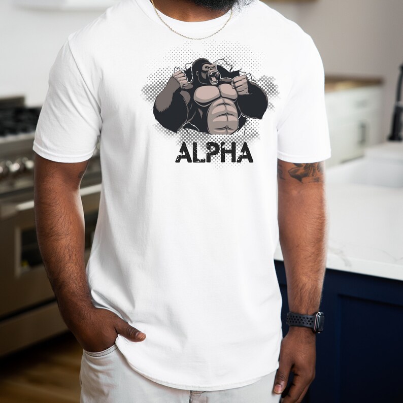 May include: White t-shirt with a graphic of a gorilla breaking through a wall with the word "ALPHA" printed below.