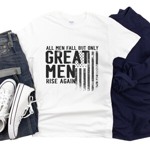 Puede incluir: Camiseta blanca con un gr&aacute;fico negro que dice "Todos los hombres caen, pero solo los grandes hombres se levantan de nuevo." El gr&aacute;fico tambi&eacute;n incluye un dise&ntilde;o de bandera estadounidense desgastado.