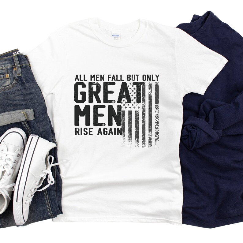 Puede incluir: Camiseta blanca con un gr&aacute;fico negro que dice "Todos los hombres caen, pero solo los grandes hombres se levantan de nuevo." El gr&aacute;fico tambi&eacute;n incluye un dise&ntilde;o de bandera estadounidense desgastado.