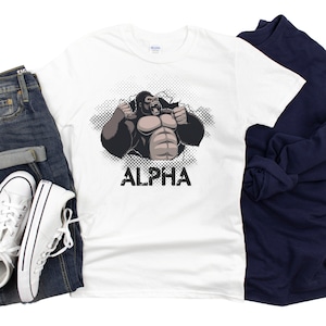May include: White t-shirt with a graphic of a gorilla breaking through a wall with the word "ALPHA" printed below.
