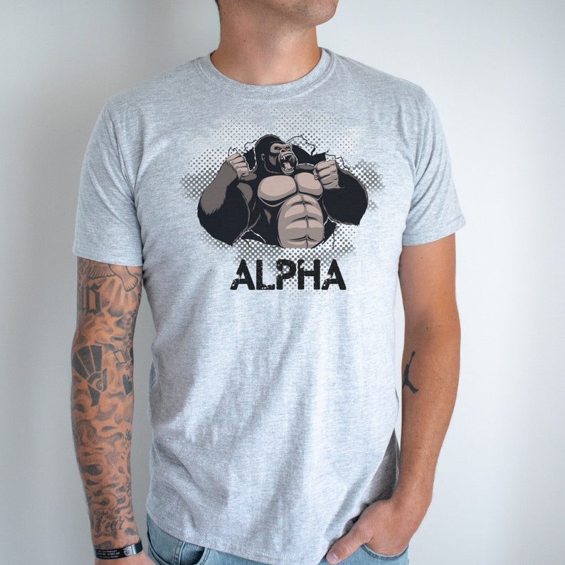 May include: A gray t-shirt with a graphic of a gorilla breaking through a wall. The gorilla is flexing its muscles and roaring. The text "ALPHA" is printed below the gorilla.