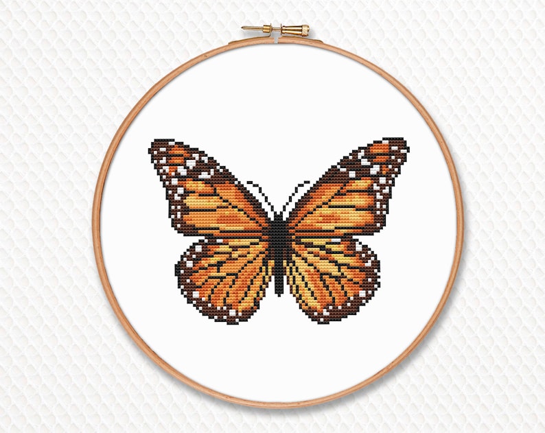 May include: A cross-stitch pattern of a monarch butterfly with orange, black, and white wings.