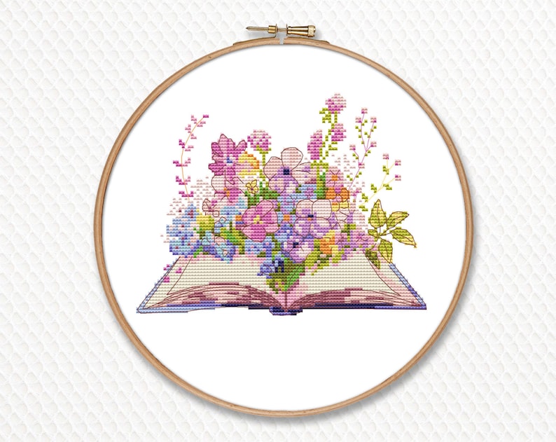 Peut inclure: Un motif de point de croix d'un livre ouvert avec un bouquet de fleurs roses, violettes et jaunes.