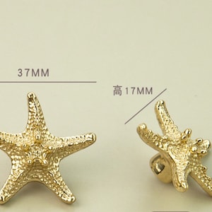 K&ouml;nnte beinhalten: Goldfarbene Schrankkn&ouml;pfe in Form von Seesternen. Die Kn&ouml;pfe sind 3,7 cm breit und 1,7 cm hoch. Die Seesterne haben eine strukturierte Oberfl&auml;che und sind als dekorative Beschl&auml;ge f&uuml;r Schubladen oder Schr&auml;nke konzipiert.