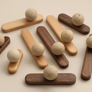 May include: A collection of wooden decorative objects. Each piece features a light-colored sphere atop a rectangular base. The bases vary in color, including light and dark wood tones. The spheres have a textured, speckled appearance.