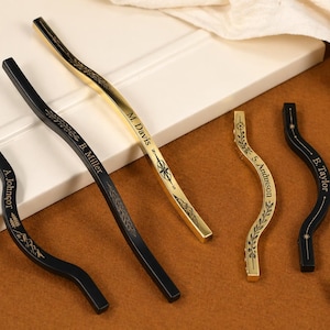 May include: A selection of decorative cabinet pulls in gold and black. The pulls feature a curved design with engraved names and floral patterns. The names include "A. Johnson", "B. Miller", "M. Davis", "S. Anderson", and "E. Taylor".
