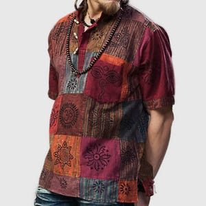 May include: A short-sleeved, multi-coloured shirt with a patchwork design. The shirt features various symbols and patterns, including a sun, a flower, and an Om symbol. The shirt has a button-up collar and a relaxed fit.