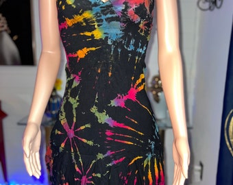 Può includere: Un abito nero senza maniche con un vivace motivo tie-dye nei toni del blu, giallo, arancione e rosa. Il capo presenta uno scollo a V, sottili spalline e un orlo asimmetrico con volant che cade sopra il ginocchio.