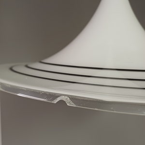 May include: A white glass lampshade with a wide, circular base and three black bands around the rim. The base is slightly chipped.