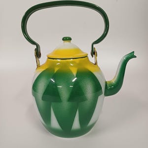 May include: An enamel teapot featuring a white base with a green and yellow gradient pattern. The teapot has a curved green handle, a matching green spout, and a removable lid with a small green knob. The body displays a geometric diamond design.