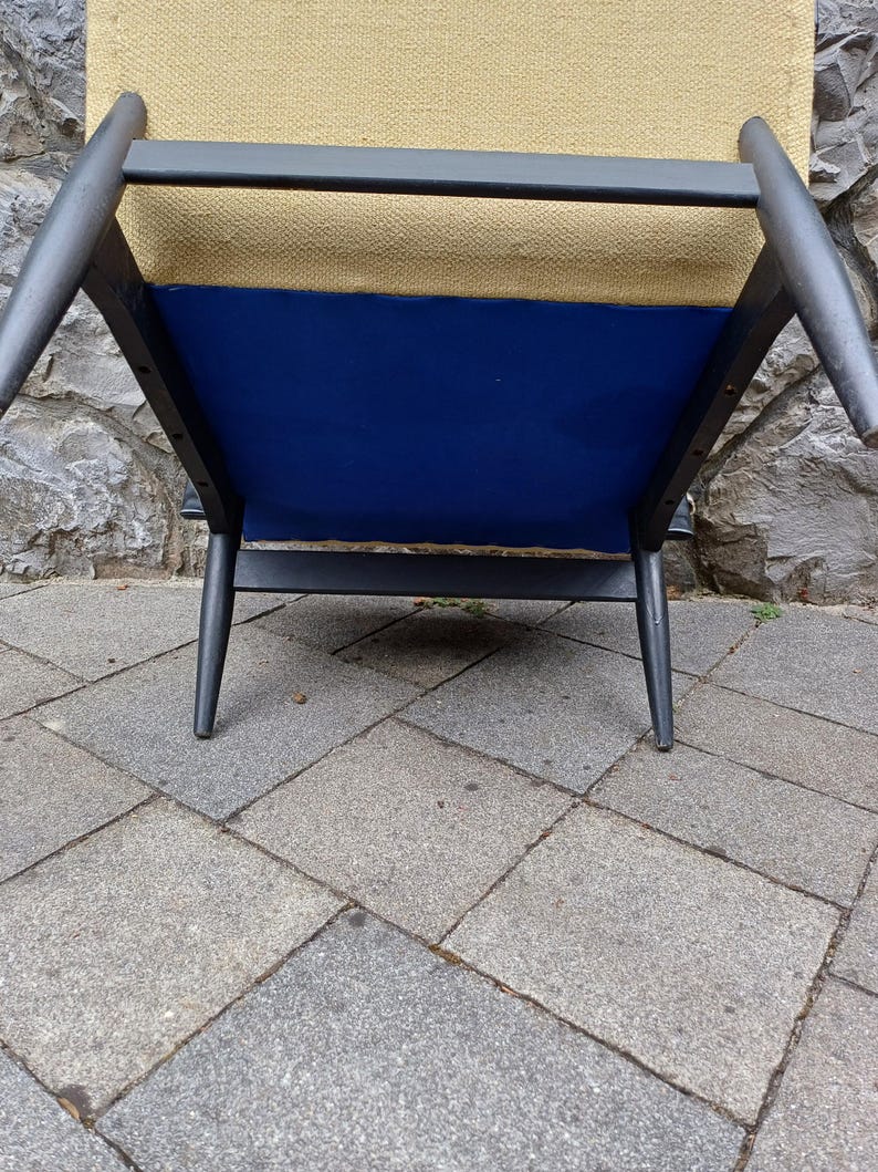 K&ouml;nnte beinhalten: Ein schwarzer Holzstuhl mit einem blauen Stoffbezug und einer beigefarbenen Stofflehne.