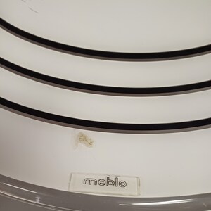 May include: White ceiling fan with three black rings and the word "meblo" printed on the bottom.
