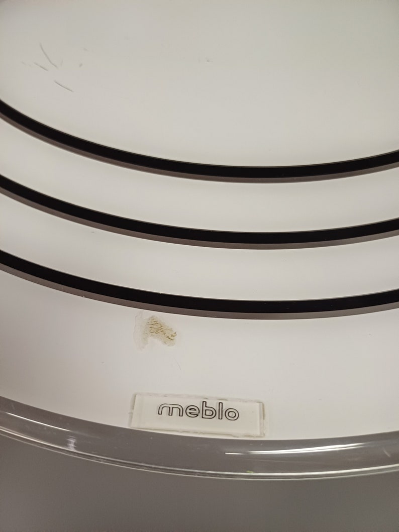 May include: White ceiling fan with three black rings and the word "meblo" printed on the bottom.
