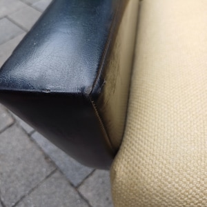 K&ouml;nnte beinhalten: Nahaufnahme einer Sofalehne mit schwarzem Lederbezug und einem beigen Stoffbezug. Das Leder ist glatt und der Stoff hat eine gewebte Struktur.