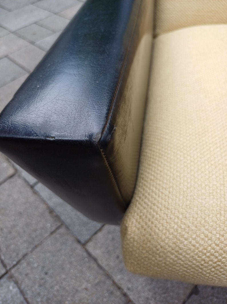 K&ouml;nnte beinhalten: Nahaufnahme einer Sofalehne mit schwarzem Lederbezug und einem beigen Stoffbezug. Das Leder ist glatt und der Stoff hat eine gewebte Struktur.
