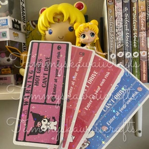 May include: A collection of colorful, rectangular stickers with holographic accents. The stickers feature text that reads "WARNING HOT GIRLS CAN'T DRIVE" and "Enter at your own risk." Each sticker has a different color and a cartoon character.