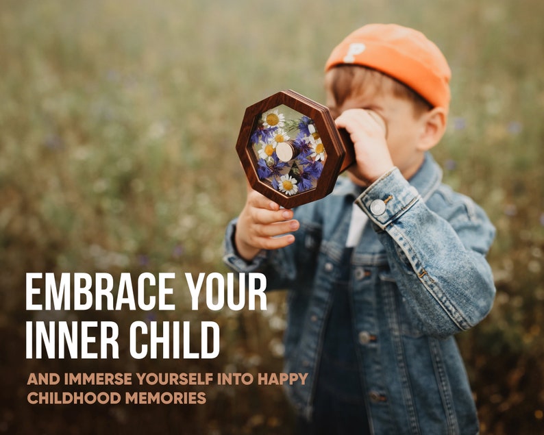 Może przedstawiać: Młoda osoba w dżinsowej kurtce i pomarańczowej czapce patrzy przez sześciokątną drewnianą ramę wypełnioną prasowanymi kwiatami. Tekst "Embrace your inner child and immerse yourself into happy childhood memories" znajduje się pod obrazem.