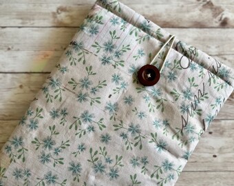May include: A beige fabric pouch with a floral pattern and a brown button closure. The pouch has a label that says "Fredapolly".